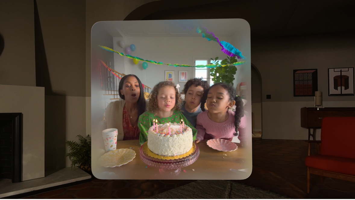 A family blows out candles on a birthday cake in a photo — that's floating in a frame in midair, in a living room. This is a still from the WWDC23 Keynote that introduced Apple Vision Pro. It's an example of how spatial photos work.